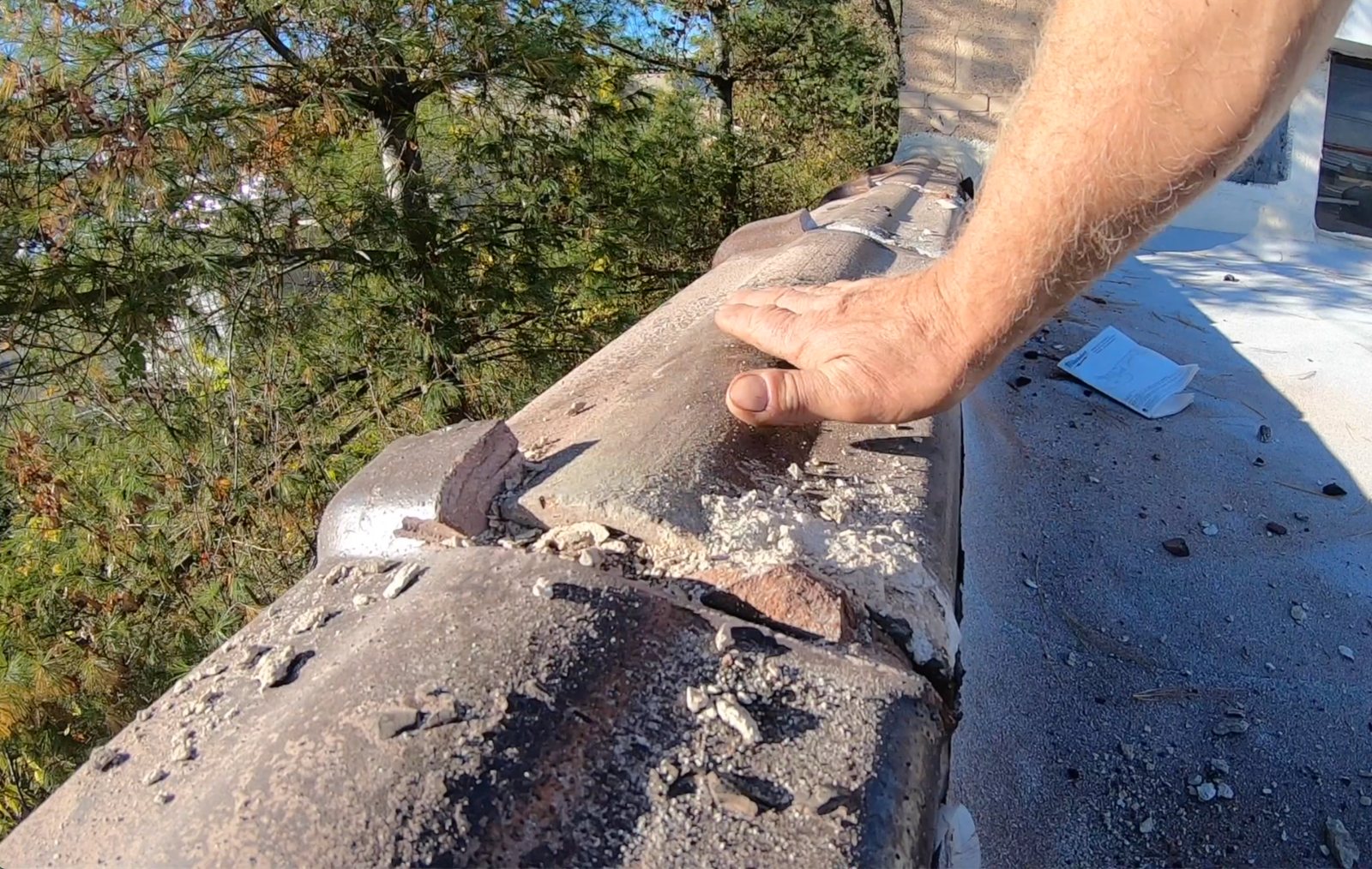 Roofing membrane over half-round clay parapet caps — Before repair