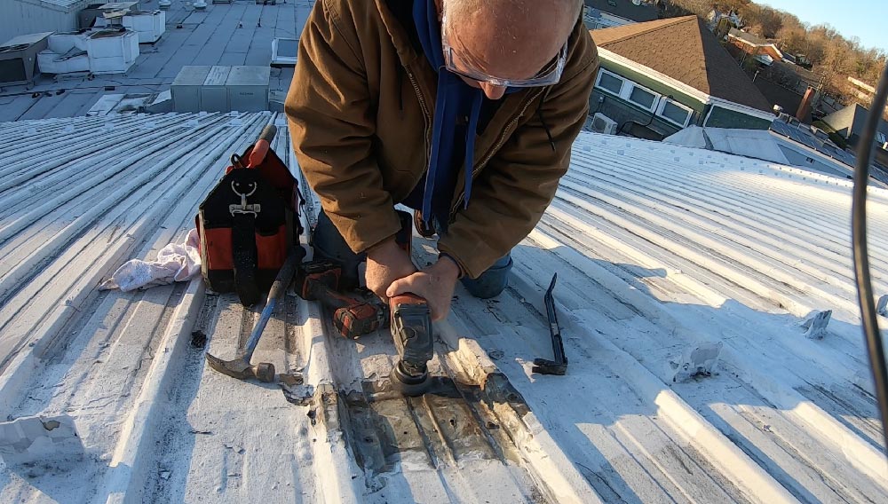 Use an angle grinder with stiff metal bristles to remove and clean a metal roof seam